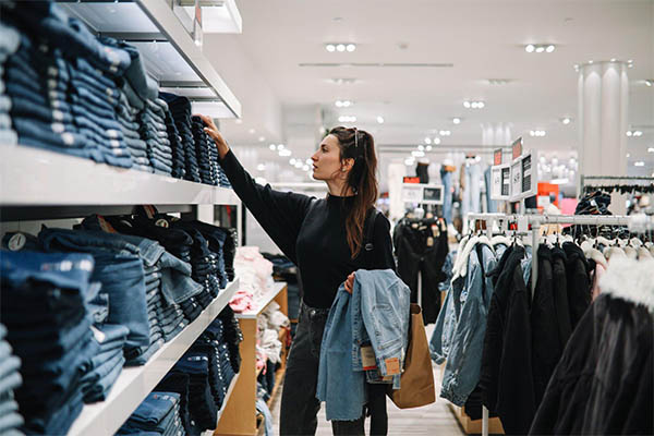 mulher jovem comprando calça jeans em loja